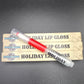 Red lip gloss with 'Holiday' text on a gray background